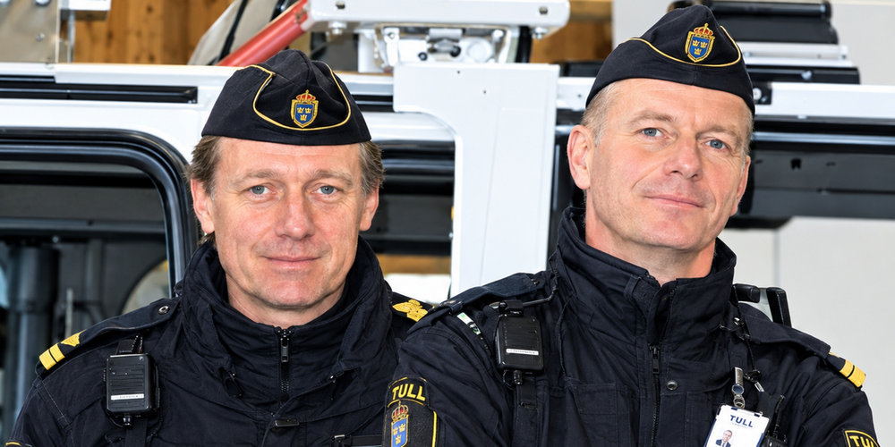 Två svenska tulltjänstemän i uniform står bredvid varandra och tittar mot kameran.