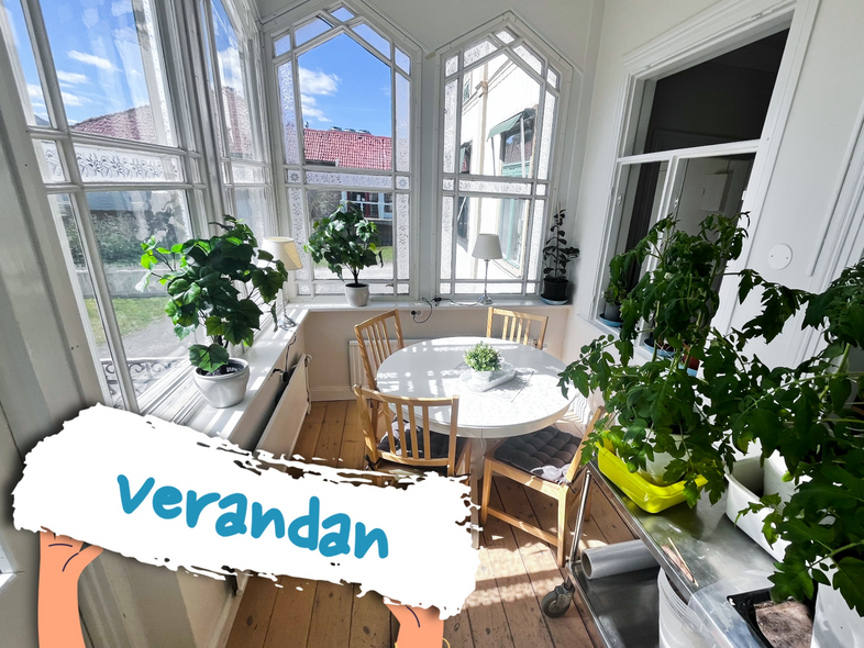Ljus veranda med stora fönster, gröna växter, runt bord och trästolar. Texten 'verandan' syns i förgrunden.