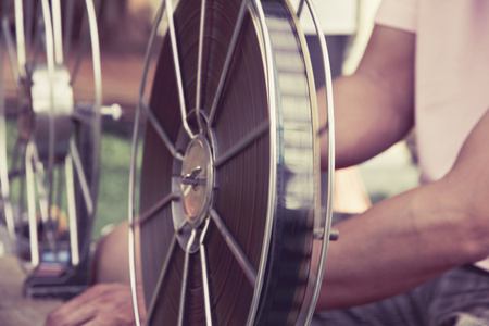 En person hanterar stora filmrullar med filmremsa på ett bord, fokus på rullarna.