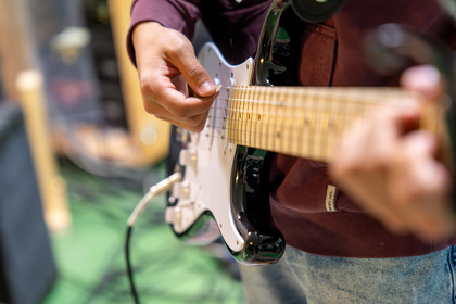 En person spelar elgitarr, närbild på händer och gitarrhals, fokus på spelteknik.