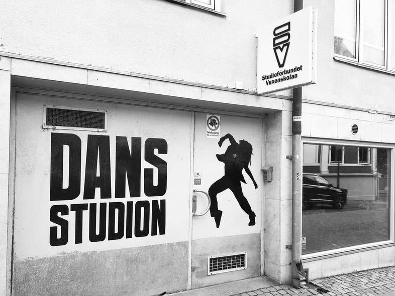Ingång till en dansstudio med stor text 'DANS STUDION' och en siluett av en dansare på dörren.