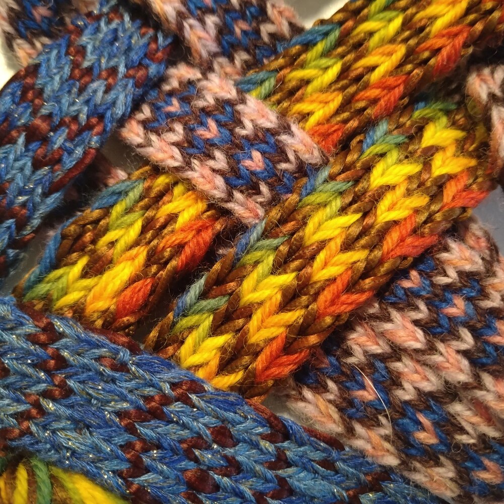Närbild av färgglada, handvävda band i blått, gult, orange och rosa garn.