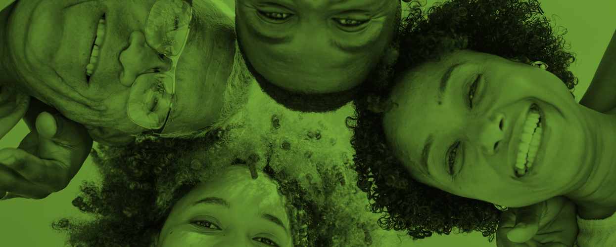 Fyra personer ligger i en cirkel och ler mot kameran, bilden har ett grönt filter.