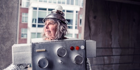 Person utklädd till robot med kartong och hushållsartiklar, står i en urban miljö.