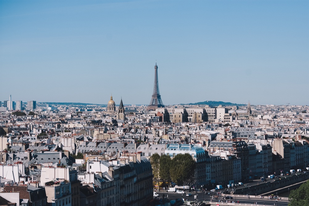 Vy över Paris med Eiffeltornet i centrum under en klarblå himmel.