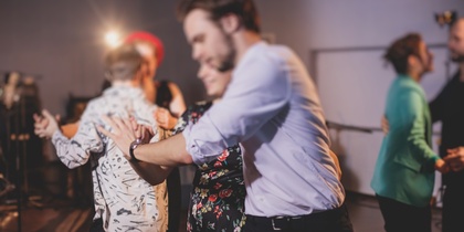 En grupp människor dansar tillsammans i ett rum med dämpad belysning.