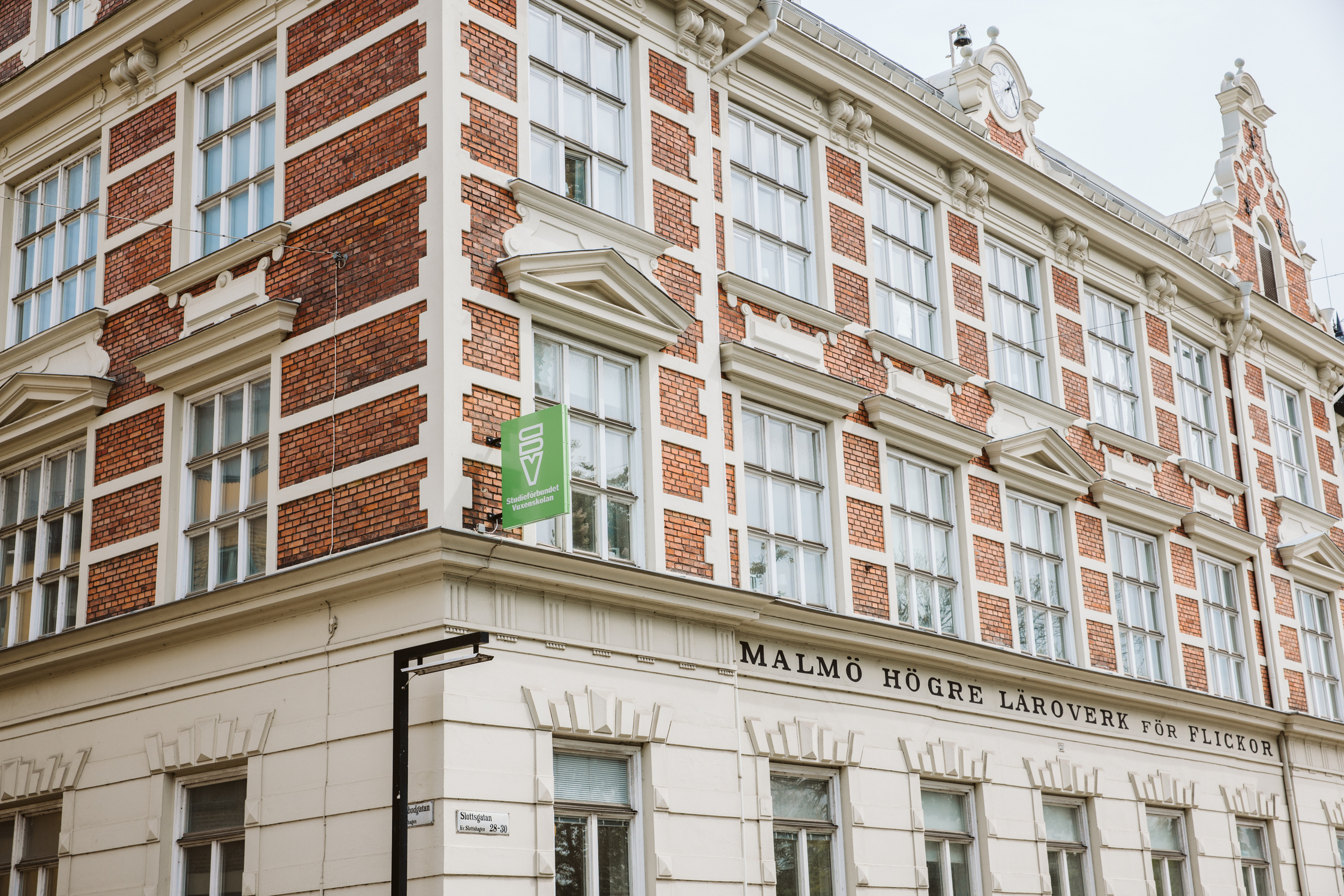 Fasad av en gammal tegel- och putsbyggnad med stora fönster och skylten 'Malmö högre läroverk'.