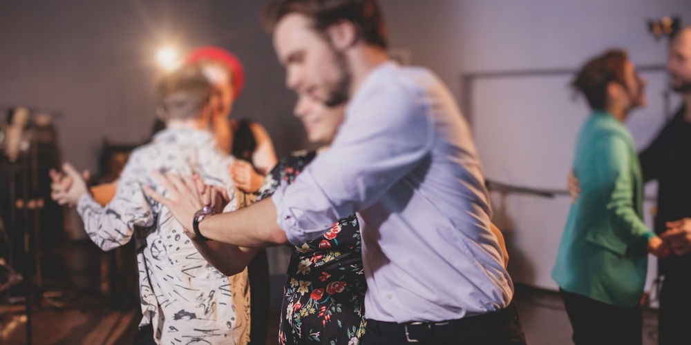 En grupp människor dansar tillsammans i ett rum med dämpad belysning.