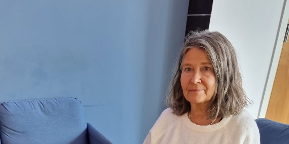 Kvinna sitter i ett vardagsrum bredvid ett soffbord med dekorationer av tyg och stenar.