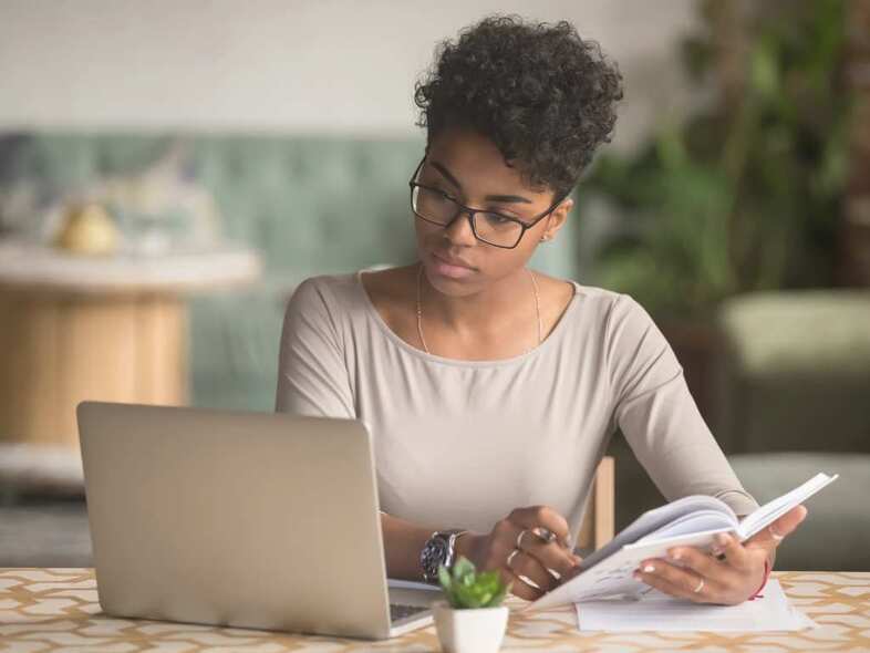 Ung kvinna sitter framför laptop och arbetar.