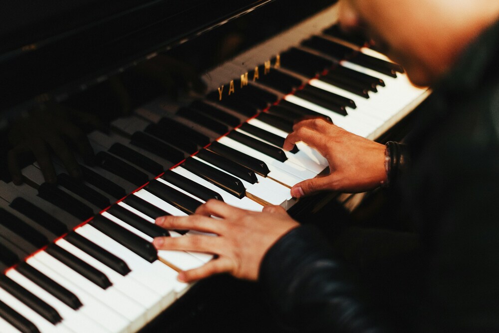 Närbild på händer som spelar på ett piano, fokus på tangenter och fingrar.